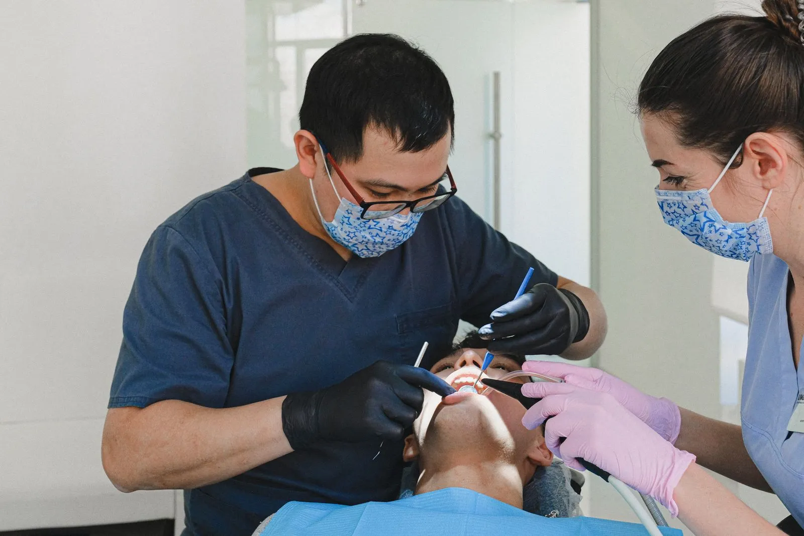 Dos profesionales atendiendo a un paciente en el sillón dental