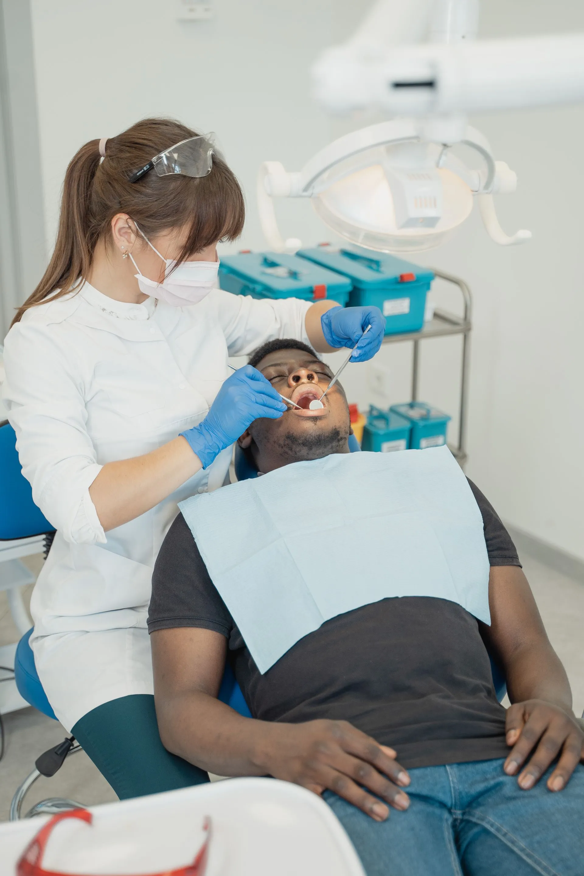Odontóloga revisando la boca de un paciente en el gabinete dental